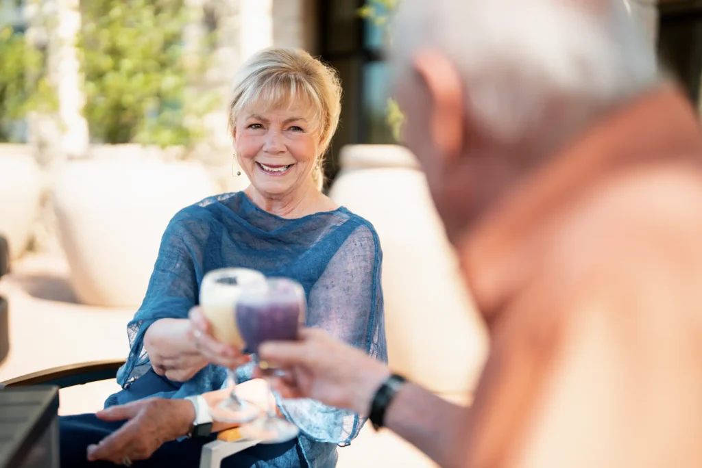 A senior couple informally raise a toast in an outdoor dining table