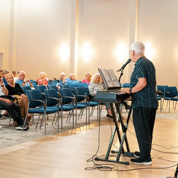 A senior pianist performs for a group of senior adults in an auditorium