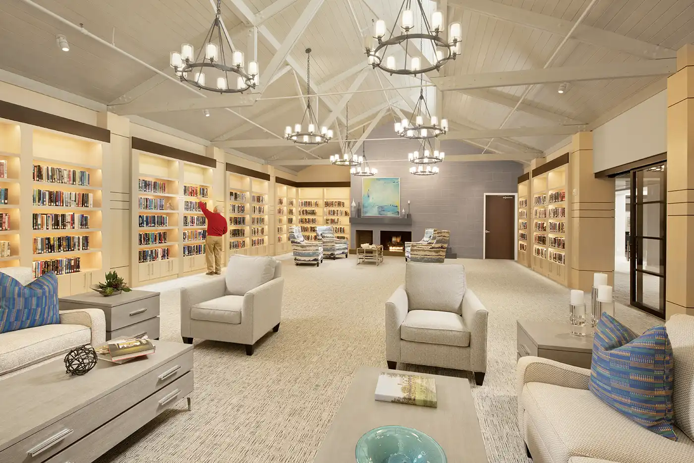 A large room with plush seating lined with illuminated bookcases along the walls