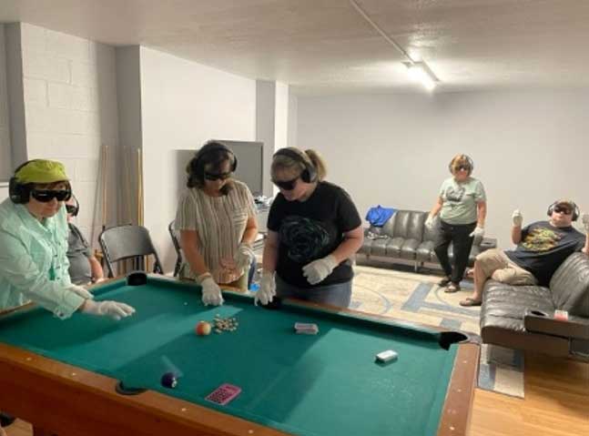 A room of people using sensory-altering equipment used in training for dementia care