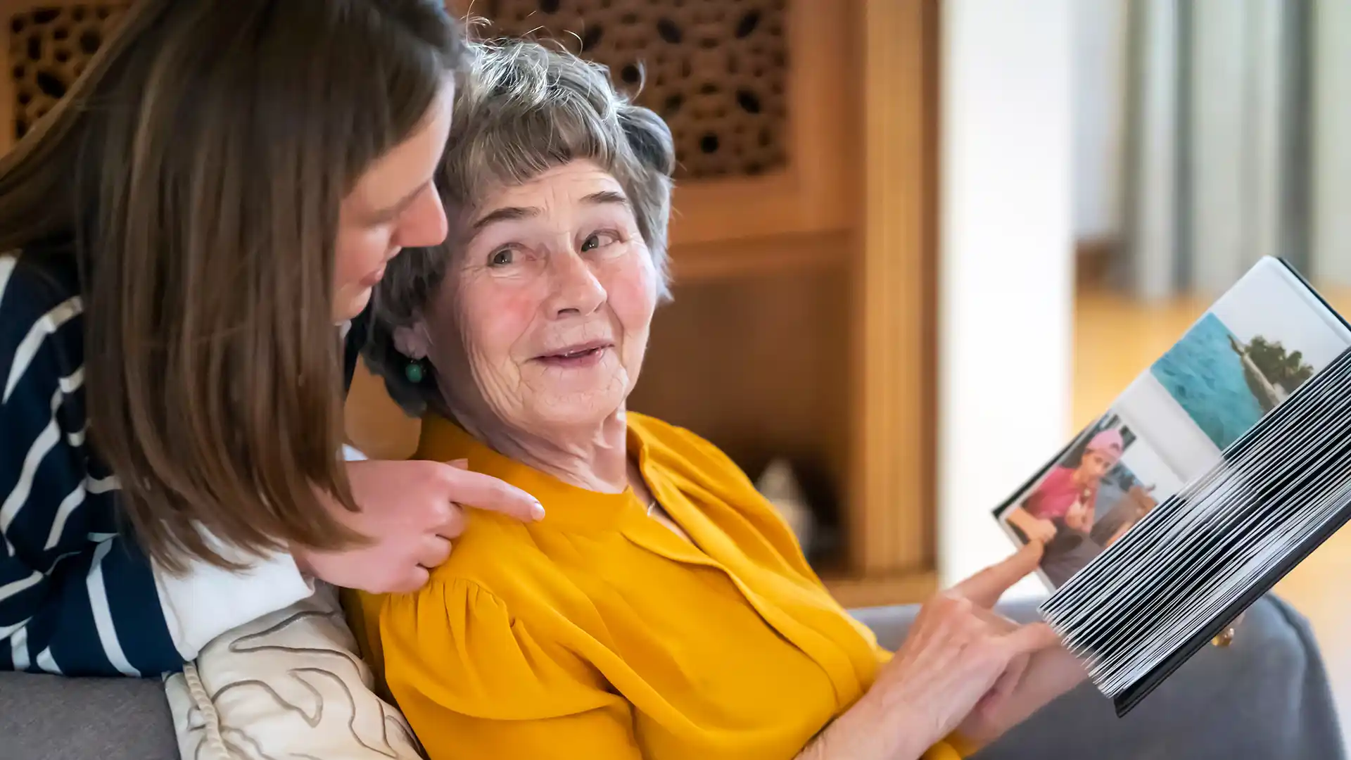 Retired woman and adult child looking through a photo album