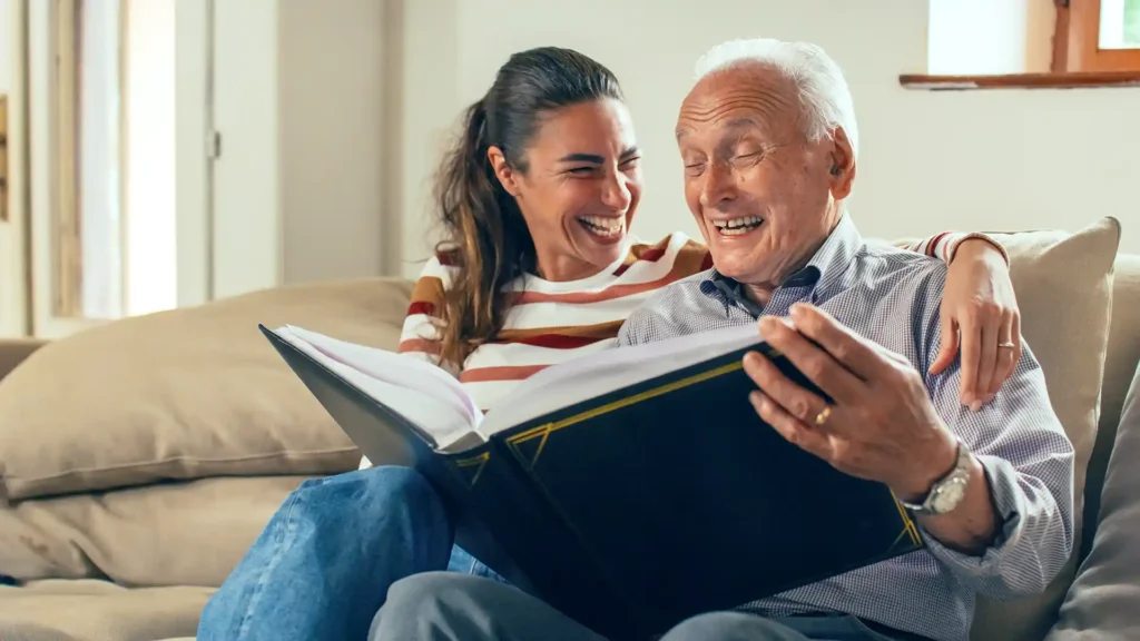 Senior and adult child enjoy looking through a photo album.