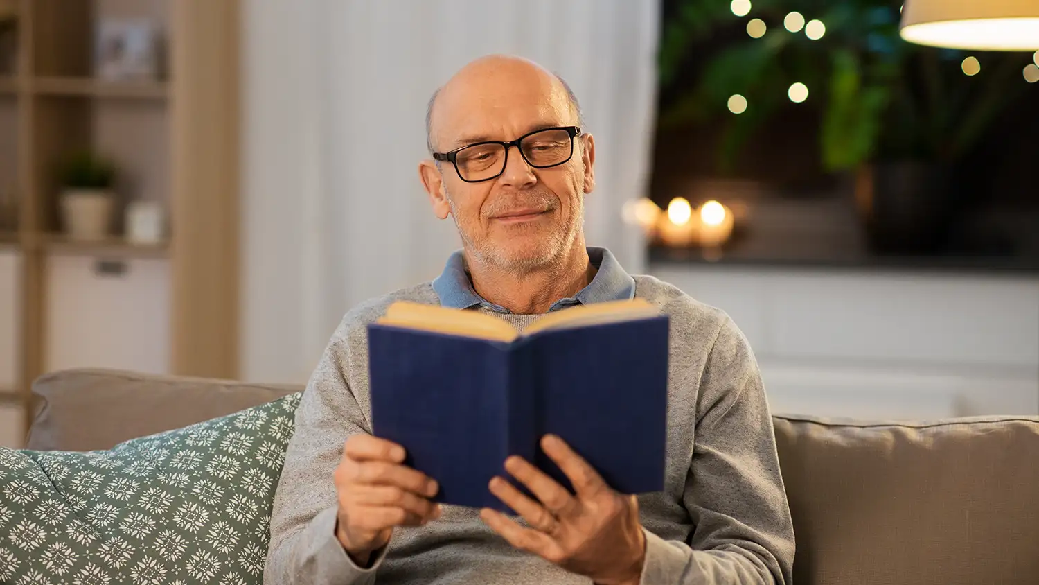Senior reading a book at night by lamplight