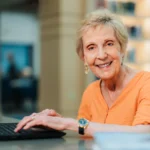 Presbyterian Village North resident enjoying time in the library using a laptop